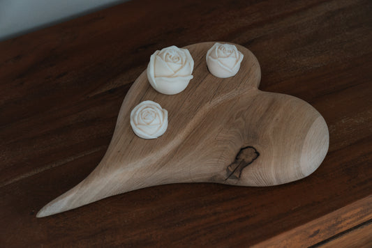 Herz aus geschliffenem Eichenholz liegend mit drei Rosenkerzen